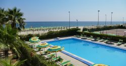Piscina con ombrelloni verde e giallo, vista mare.